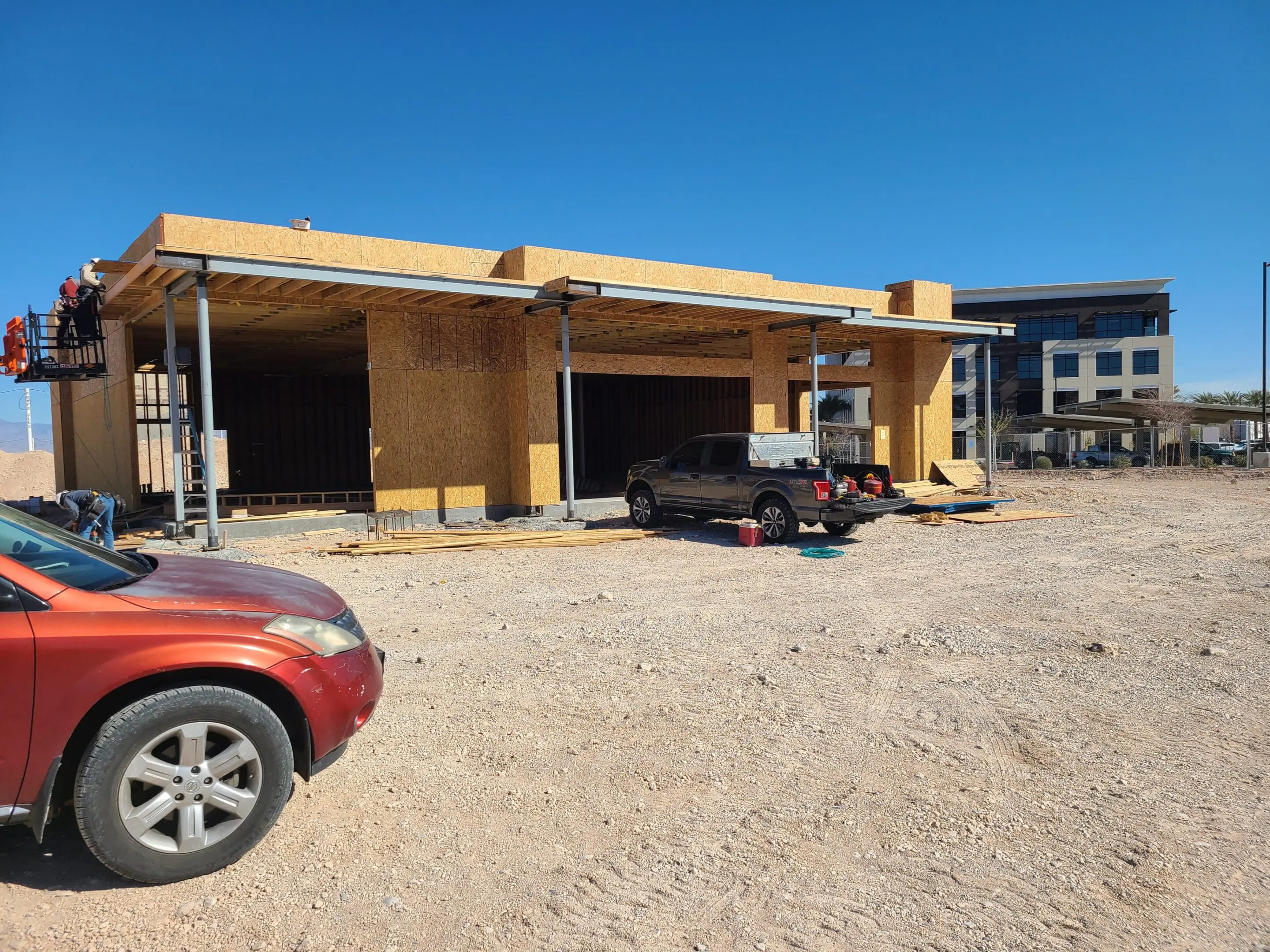 Construction site with vehicles and wooden framework under a clear sky.