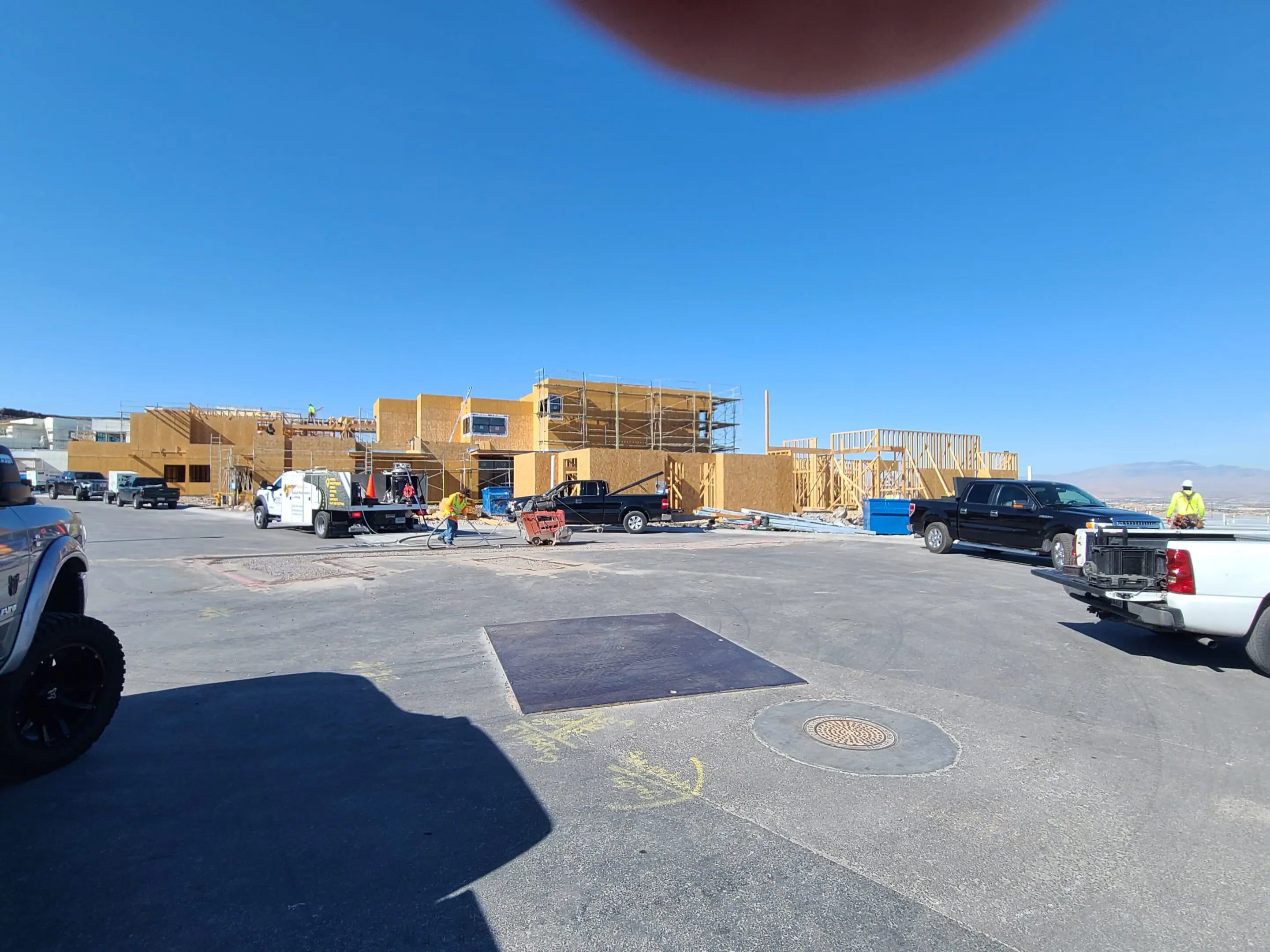 Construction site with wooden framing under clear blue sky.