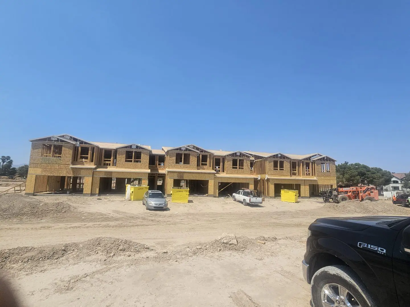 Newly constructed townhouses under a clear blue sky.