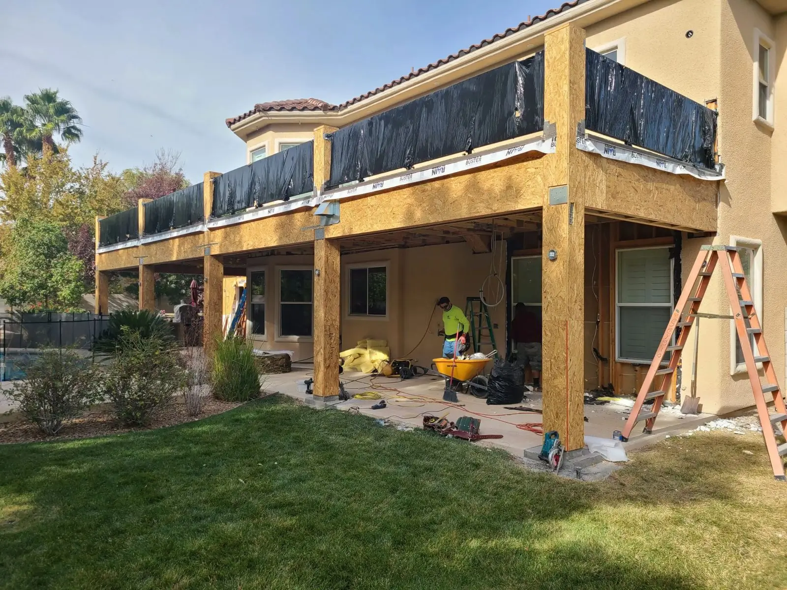 Workers renovating a two-story house with scaffolding and tools.