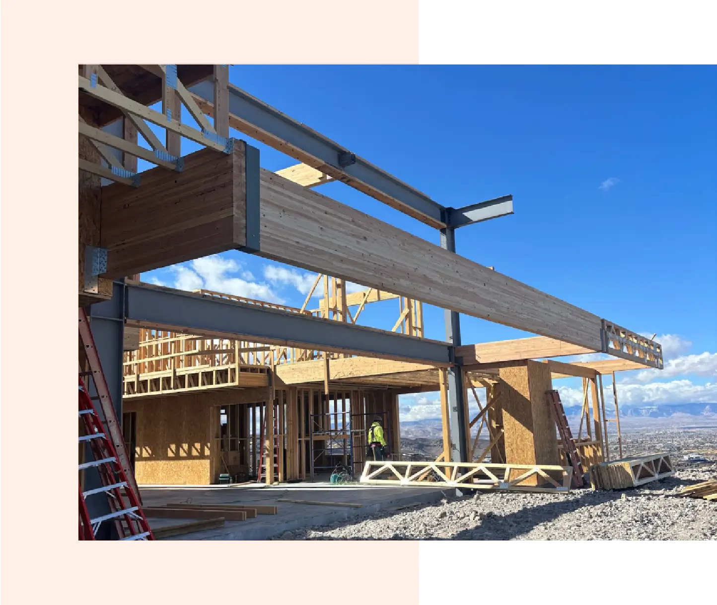 Construction site with steel beams and crane under a clear blue sky.